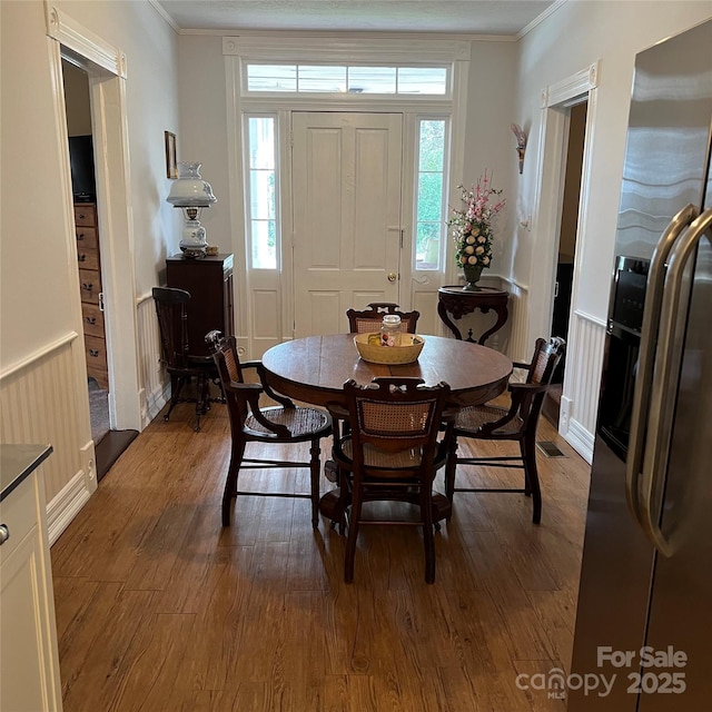 dining room featuring a wainscoted wall, crown molding, and wood finished floors