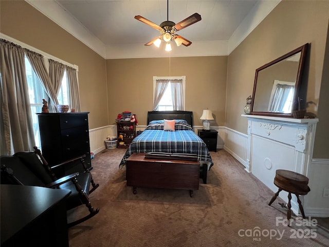 bedroom with a wainscoted wall, a ceiling fan, and carpet flooring