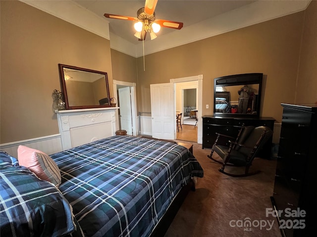 bedroom with carpet, wainscoting, a decorative wall, and lofted ceiling