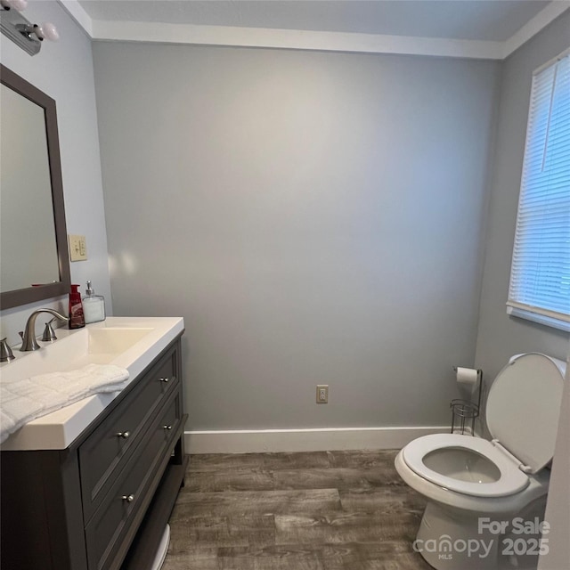 bathroom featuring toilet, vanity, baseboards, and wood finished floors