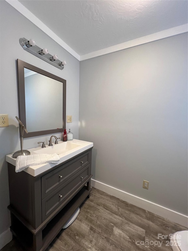 bathroom featuring a textured ceiling, wood finished floors, vanity, and baseboards