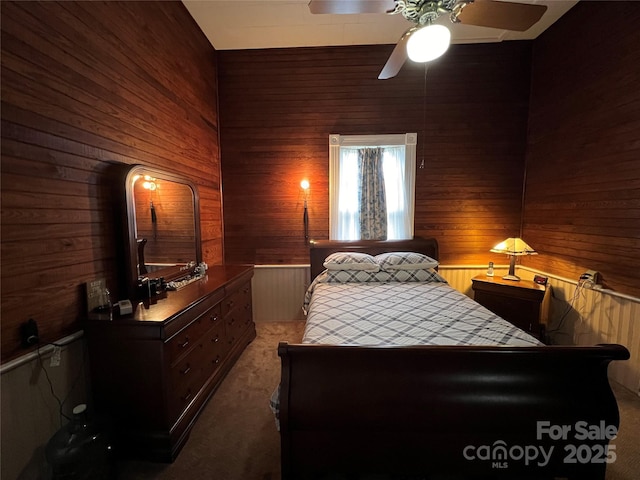 bedroom featuring light carpet, wood walls, and ceiling fan