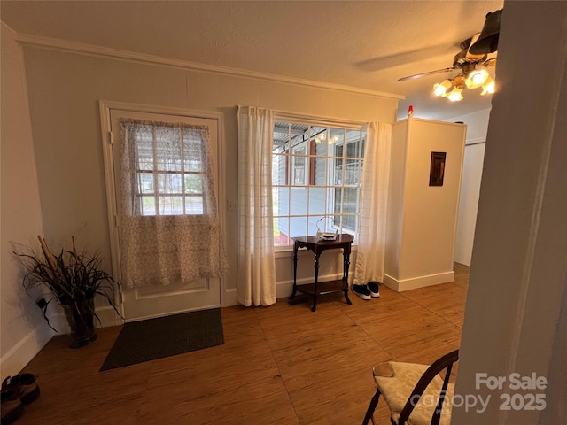 doorway to outside with baseboards, ceiling fan, ornamental molding, and wood finished floors