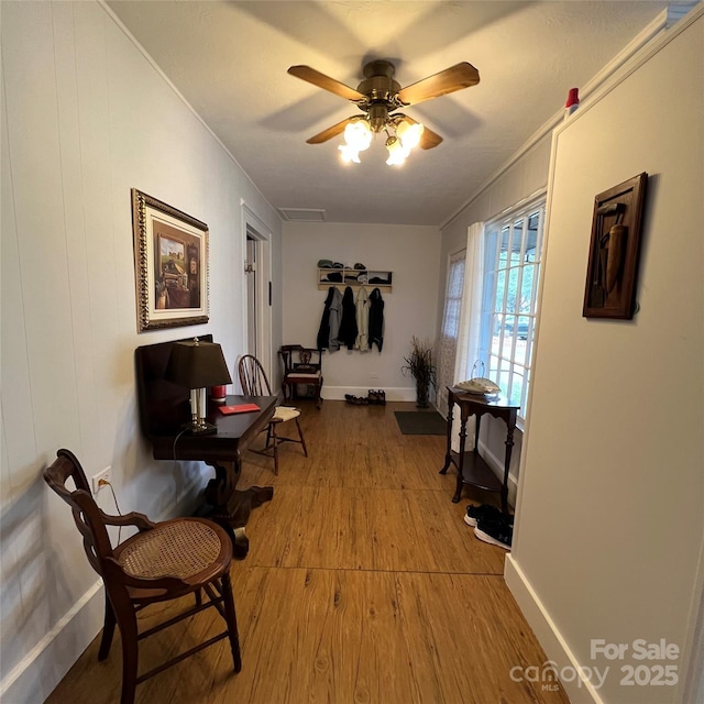 sitting room featuring a ceiling fan, visible vents, baseboards, and wood finished floors