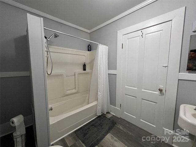 bathroom featuring ornamental molding, wood finished floors, and shower / tub combo