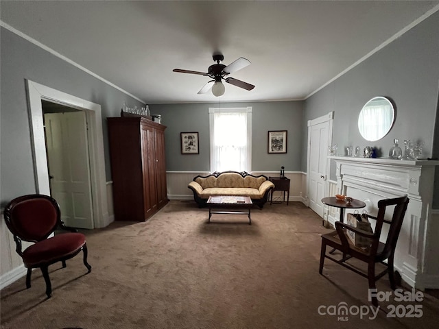 sitting room with carpet flooring, a ceiling fan, and crown molding