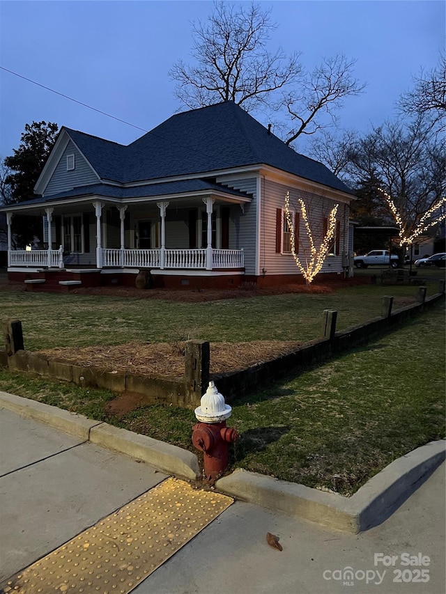 view of front of property with covered porch, a shingled roof, and a front yard