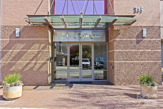 view of exterior entry featuring brick siding and french doors