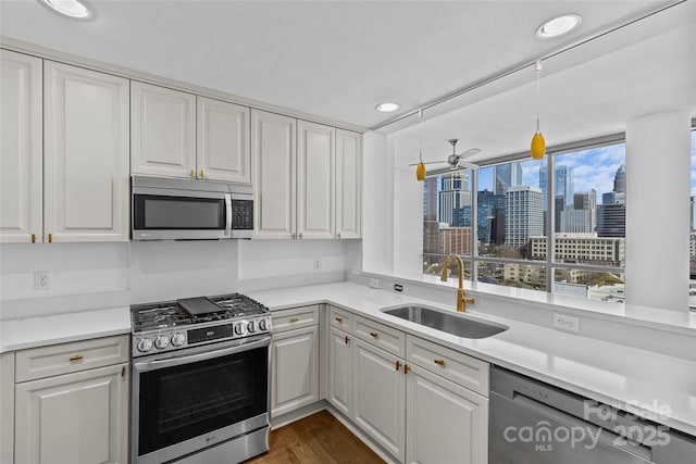 kitchen featuring stainless steel appliances, a sink, light countertops, and white cabinets