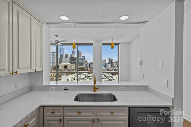 kitchen featuring a city view, decorative light fixtures, light countertops, a sink, and dishwasher