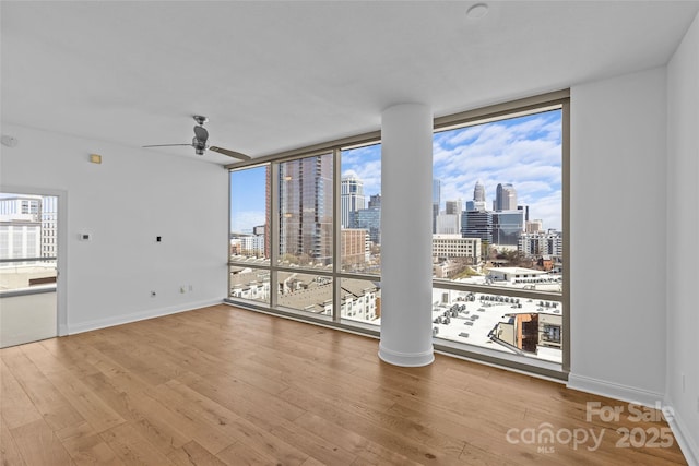 empty room featuring a city view, wood finished floors, and floor to ceiling windows