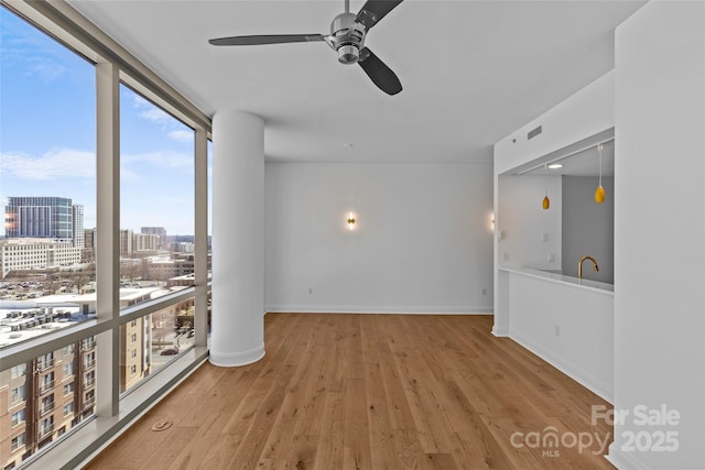 interior space featuring baseboards, visible vents, wood finished floors, expansive windows, and a city view