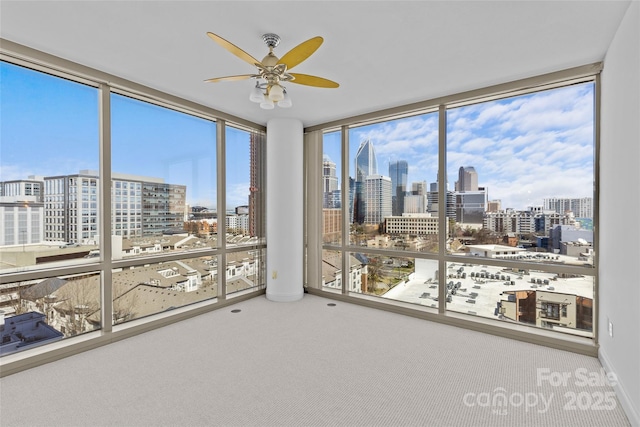 unfurnished sunroom featuring a view of city and ceiling fan