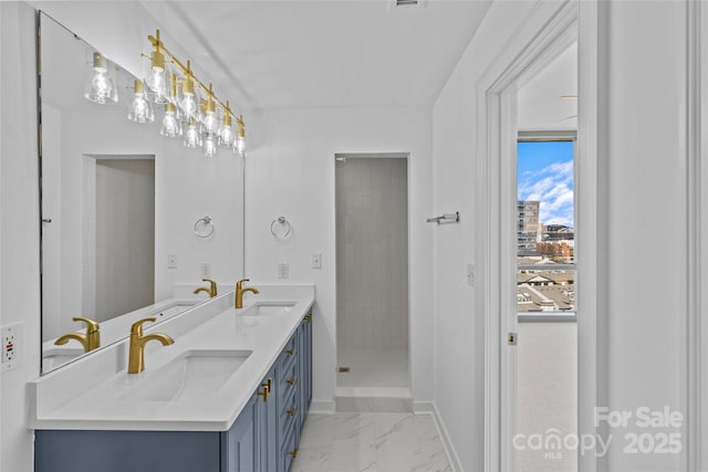 bathroom featuring marble finish floor, a sink, baseboards, and double vanity