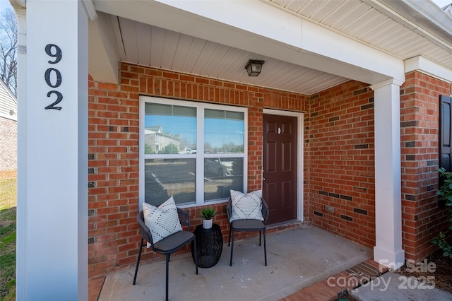 entrance to property featuring covered porch and brick siding