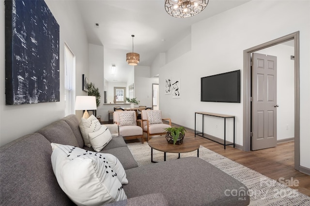 living area featuring wood finished floors, a towering ceiling, and baseboards