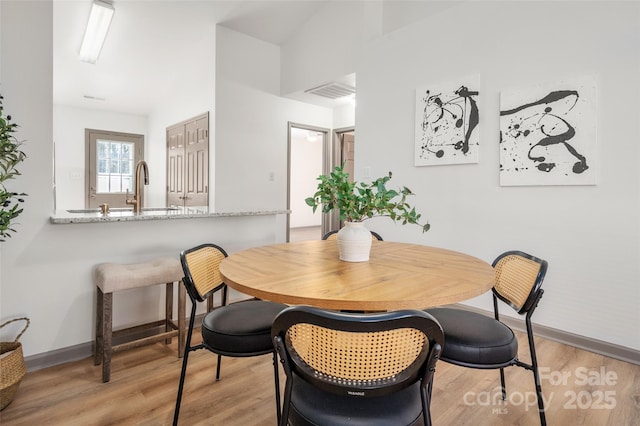 dining room featuring light wood-style floors, baseboards, and visible vents