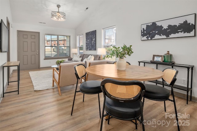 dining room with lofted ceiling, light wood-style floors, baseboards, and visible vents