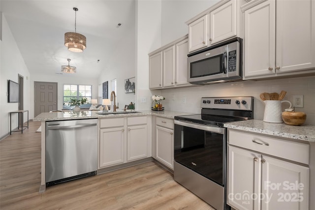 kitchen with appliances with stainless steel finishes, backsplash, a sink, and a peninsula