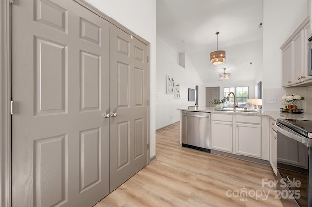 kitchen featuring a peninsula, range with electric stovetop, a sink, stainless steel dishwasher, and light wood-type flooring