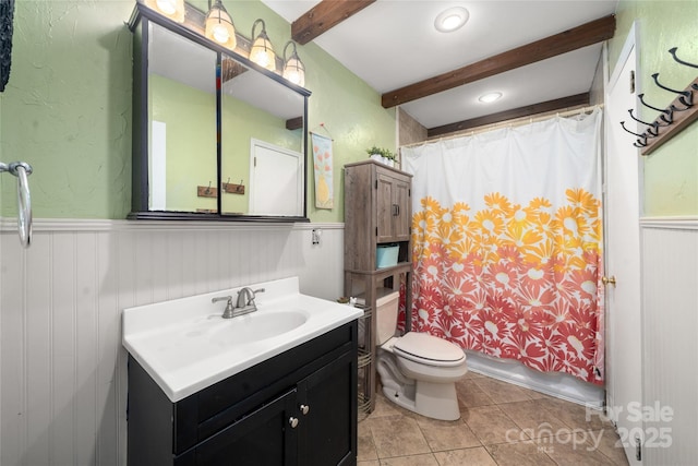 full bathroom featuring toilet, a wainscoted wall, beamed ceiling, shower / bath combination with curtain, and vanity