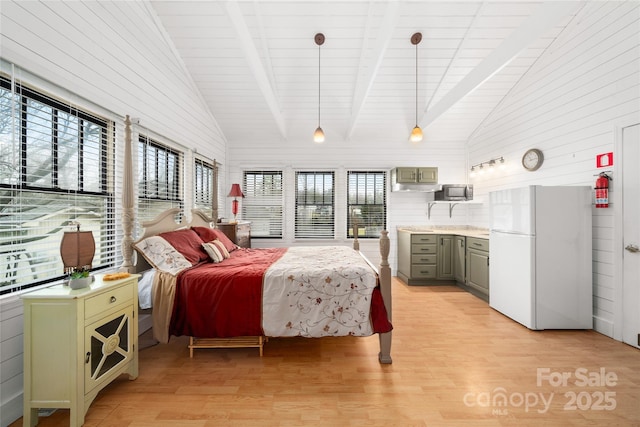 bedroom featuring light wood-style flooring, multiple windows, and freestanding refrigerator