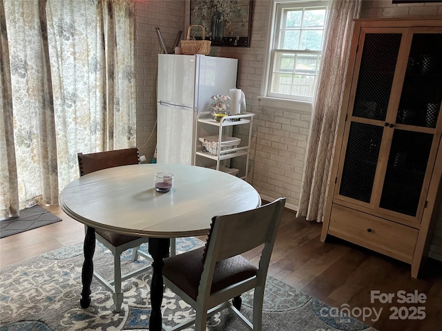 dining area featuring brick wall and wood finished floors