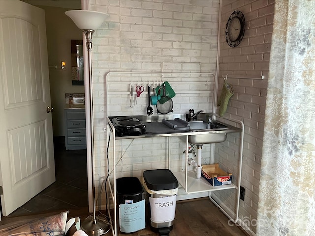 interior space with dark wood-type flooring, a sink, and brick wall