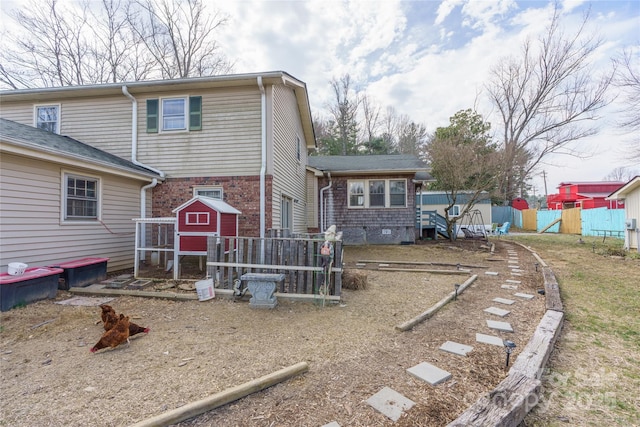 rear view of house with an outbuilding, brick siding, fence, and exterior structure