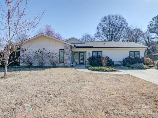 ranch-style house featuring stone siding and a front lawn