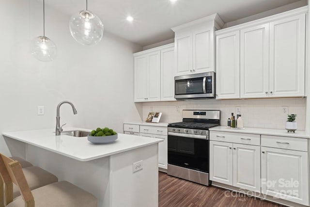 kitchen with appliances with stainless steel finishes, a sink, a kitchen bar, and tasteful backsplash