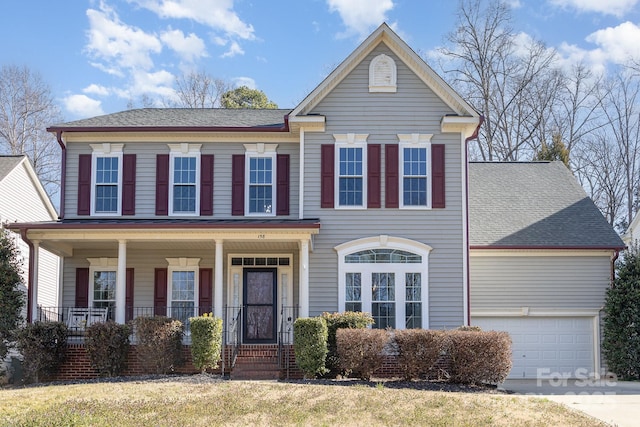 view of front facade with a garage, driveway, a porch, and a shingled roof