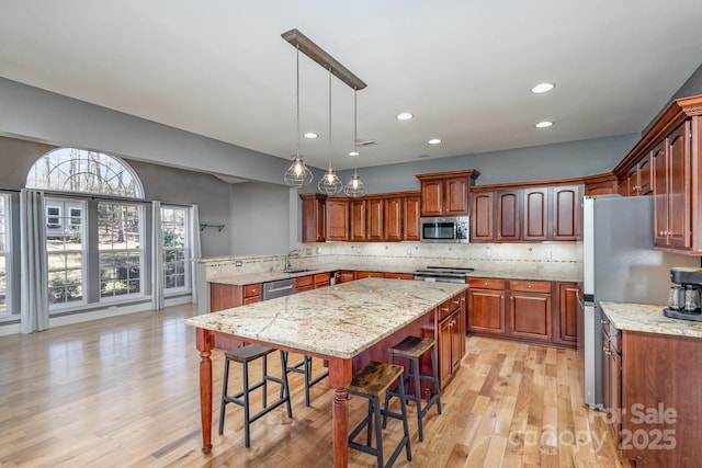 kitchen with tasteful backsplash, appliances with stainless steel finishes, a breakfast bar, and light wood-style floors