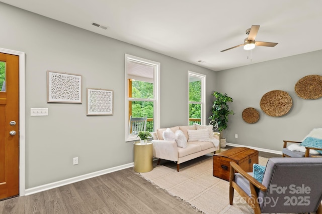 living area with baseboards, ceiling fan, visible vents, and light wood-style floors