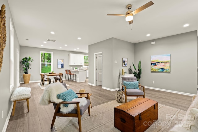 living room with light wood-type flooring, visible vents, and recessed lighting