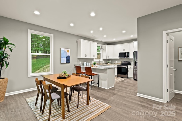 dining area with baseboards, light wood-type flooring, and recessed lighting