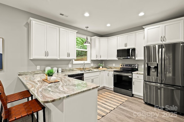 kitchen featuring a peninsula, appliances with stainless steel finishes, visible vents, and white cabinetry