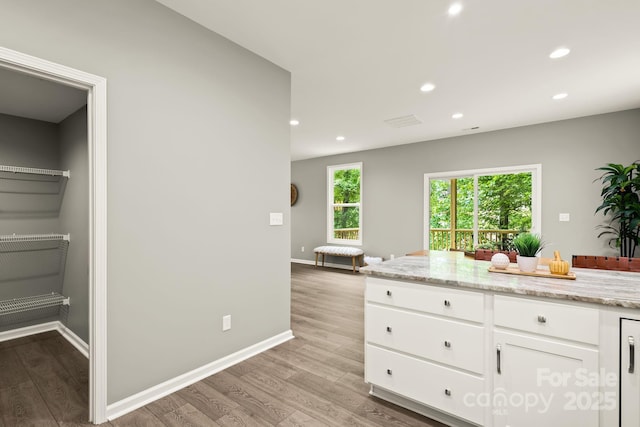 kitchen with baseboards, light stone countertops, light wood-type flooring, white cabinetry, and recessed lighting