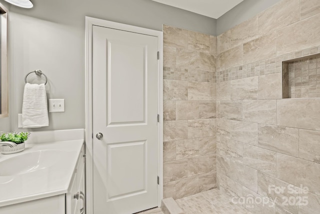 full bath with a tile shower and vanity