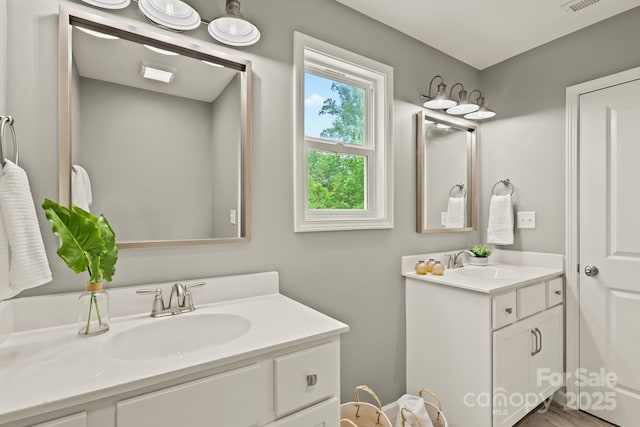 bathroom featuring two vanities, a sink, and visible vents