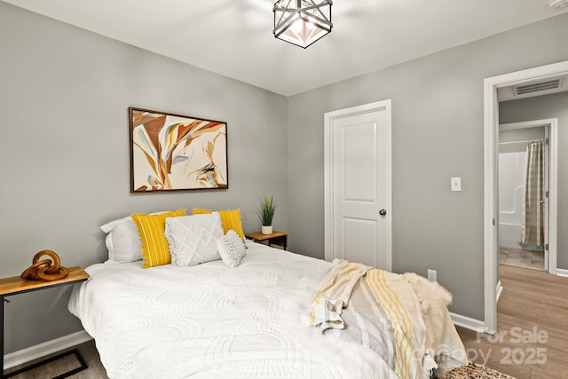 bedroom featuring baseboards, visible vents, and wood finished floors