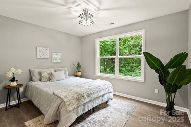 bedroom with visible vents, baseboards, and wood finished floors