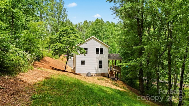 rear view of house with a deck, stairs, a yard, crawl space, and a wooded view