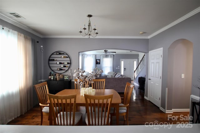 dining area with arched walkways, crown molding, visible vents, wood finished floors, and stairs