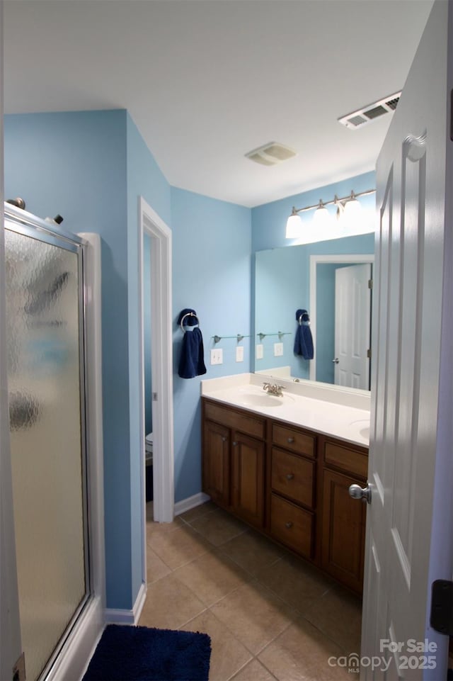 full bathroom featuring double vanity, a stall shower, baseboards, visible vents, and tile patterned floors