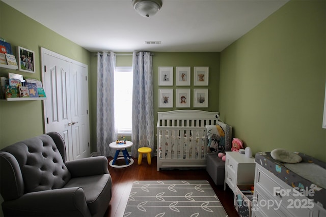 bedroom featuring dark wood-style floors, a closet, and visible vents