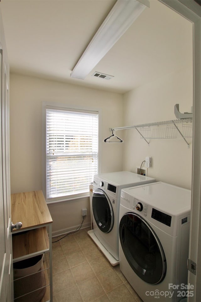 laundry room featuring washing machine and clothes dryer, light tile patterned floors, visible vents, laundry area, and baseboards