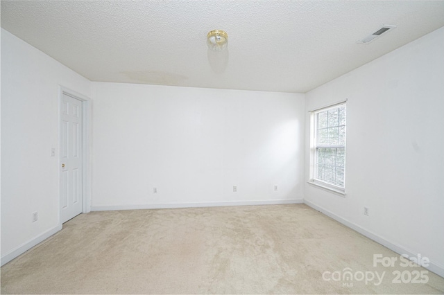 unfurnished room with baseboards, light colored carpet, visible vents, and a textured ceiling