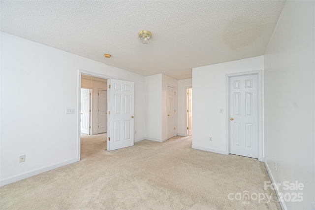 unfurnished bedroom featuring light colored carpet, baseboards, and a textured ceiling