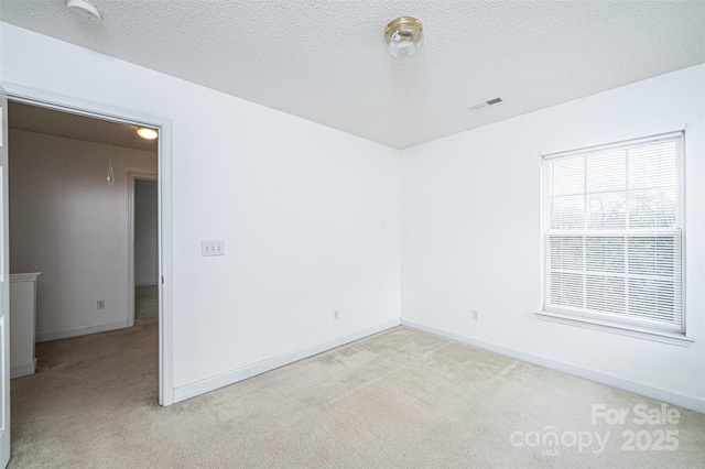 unfurnished room featuring visible vents, light colored carpet, and a textured ceiling